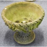 A Composite Garden Urn, of circular form with relief and foliate detail, raised on socle base,