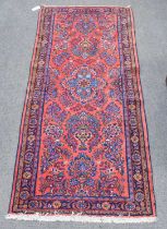 Lillian Rug, the blood red field with central flowerhead enclosed by rosette borders, 184cm by 80cm,