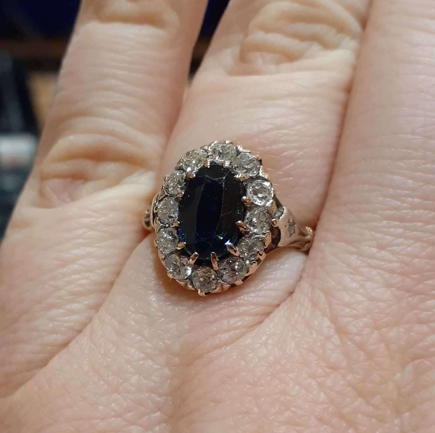 A Sapphire and Diamond Cluster Ring the oval cut sapphire within a border of old cut diamonds, in - Image 2 of 5