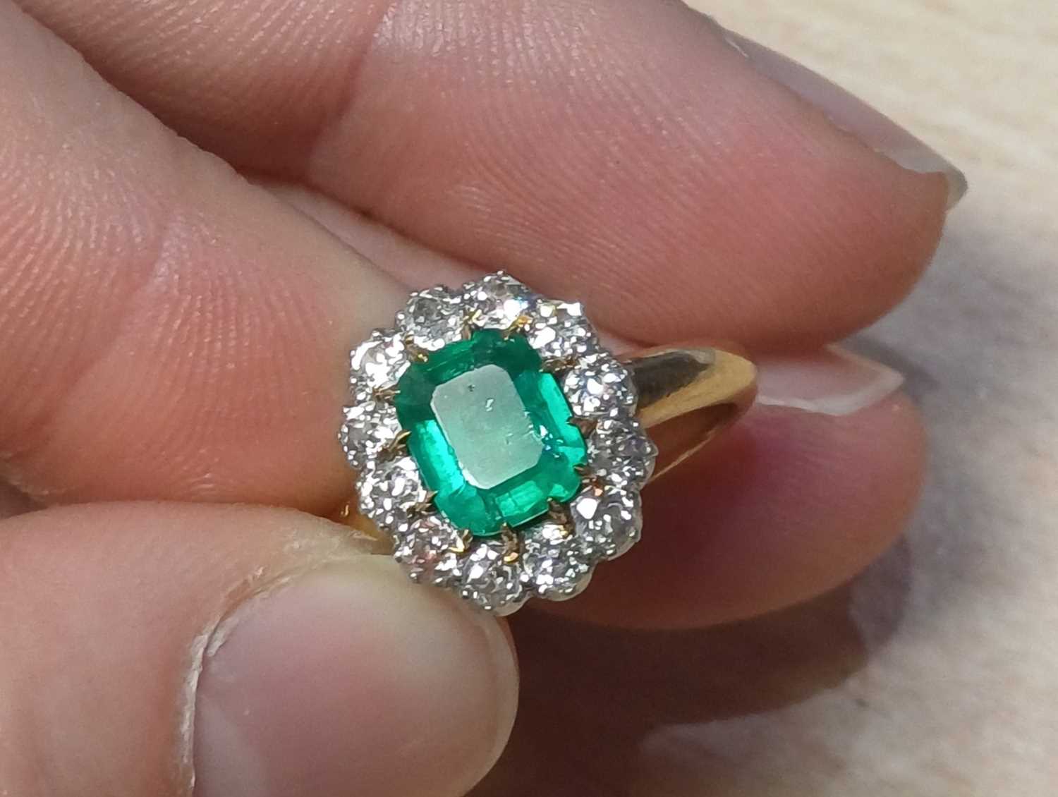 An Emerald and Diamond Cluster Ring the emerald-cut emerald in a yellow claw setting, within a - Image 9 of 9