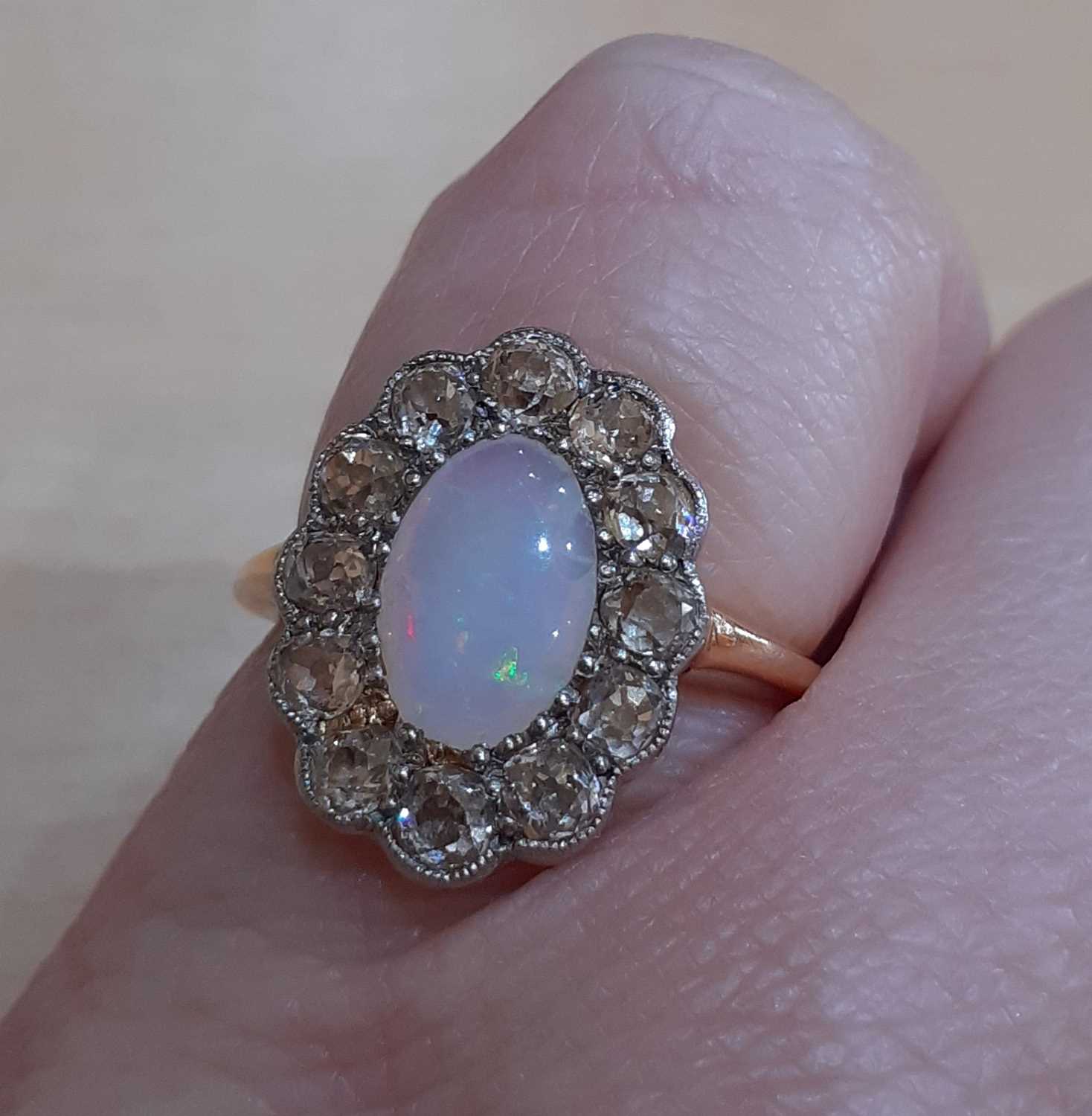 An Opal and Diamond Cluster Ring the oval opal within a border of old cut diamonds, in white - Image 2 of 5