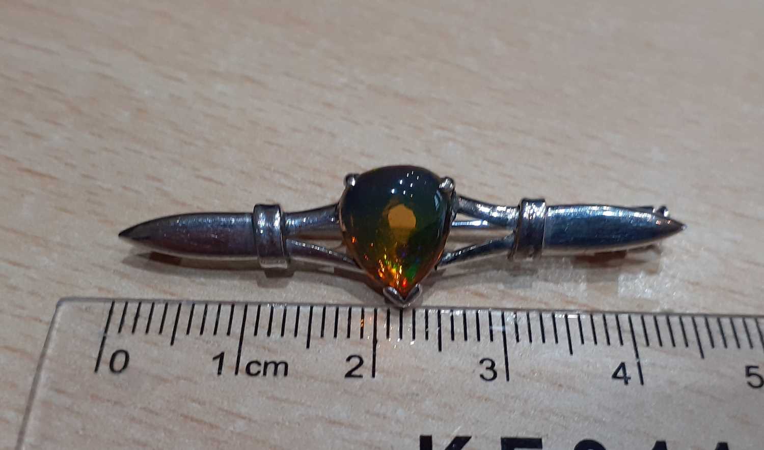 A Water Opal Brooch the pear cabochon water opal in a white claw setting, to a tapered bar length - Image 2 of 3