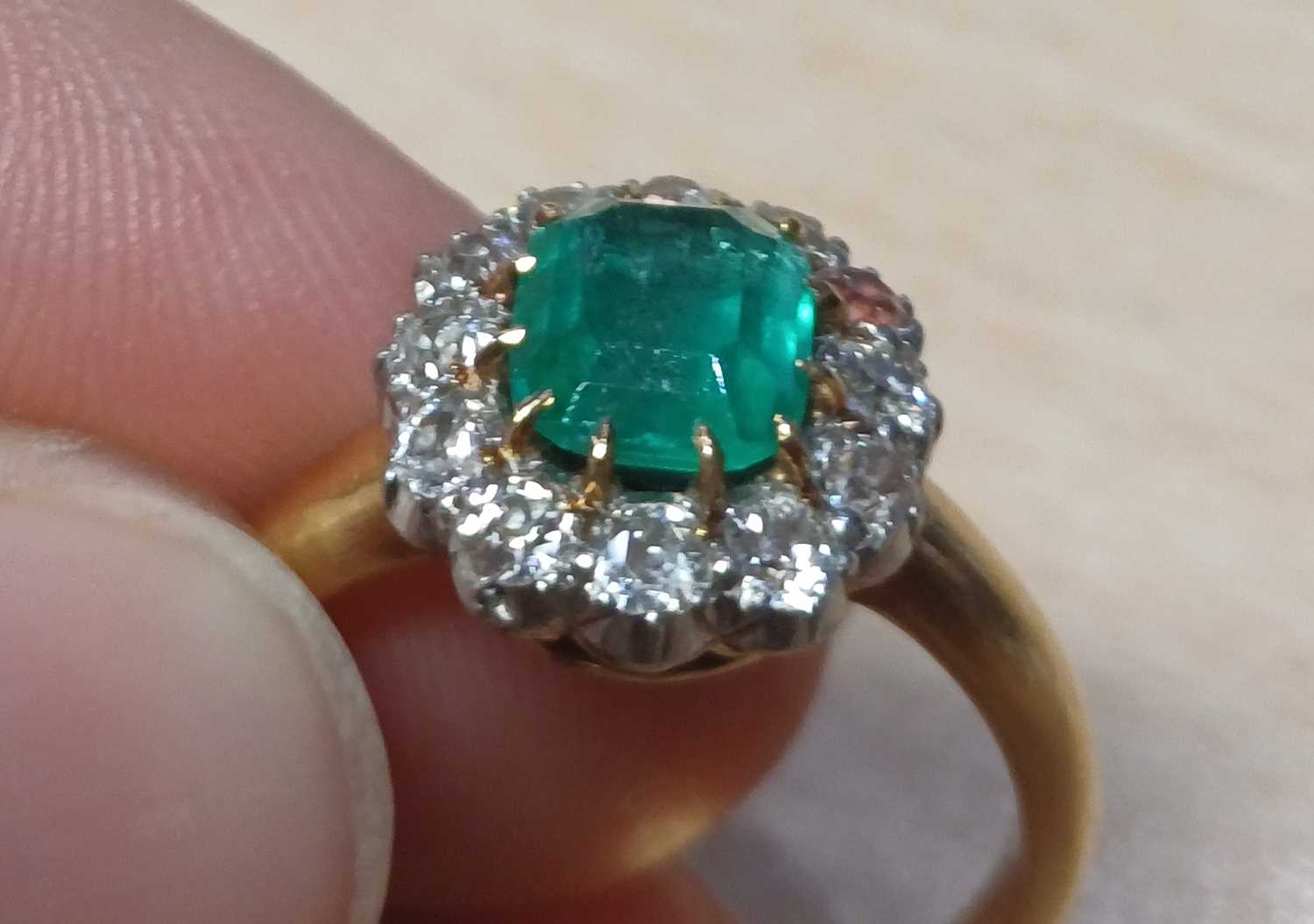An Emerald and Diamond Cluster Ring the emerald-cut emerald in a yellow claw setting, within a - Image 6 of 9