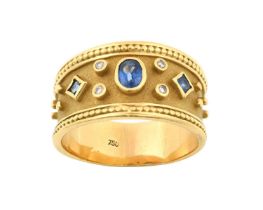 A Sapphire and Diamond Ring the oval cut sapphire flanked by a square cut sapphire to either side,