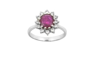 An 18 Carat White Gold Ruby and Diamond Cluster Ring the oval cut ruby within a border of round