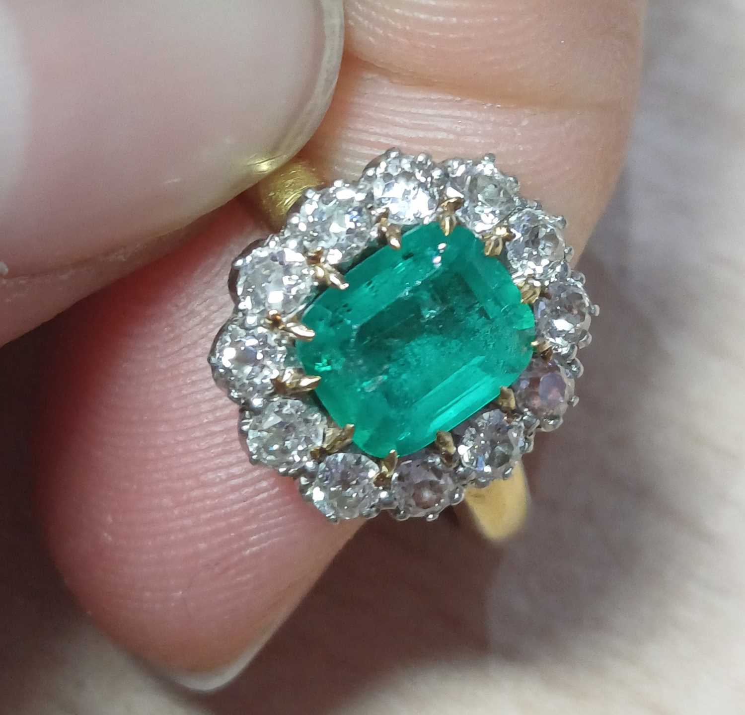 An Emerald and Diamond Cluster Ring the emerald-cut emerald in a yellow claw setting, within a - Image 8 of 9