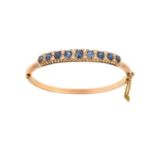 A Sapphire and Diamond Hinged Bangle nine graduated oval cut sapphires spaced by pairs of old cut