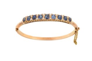 A Sapphire and Diamond Hinged Bangle nine graduated oval cut sapphires spaced by pairs of old cut