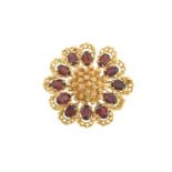 An 18 Carat Gold Garnet Brooch modelled as a stylised flower, the centre formed of yellow textured