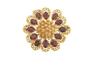 An 18 Carat Gold Garnet Brooch modelled as a stylised flower, the centre formed of yellow textured