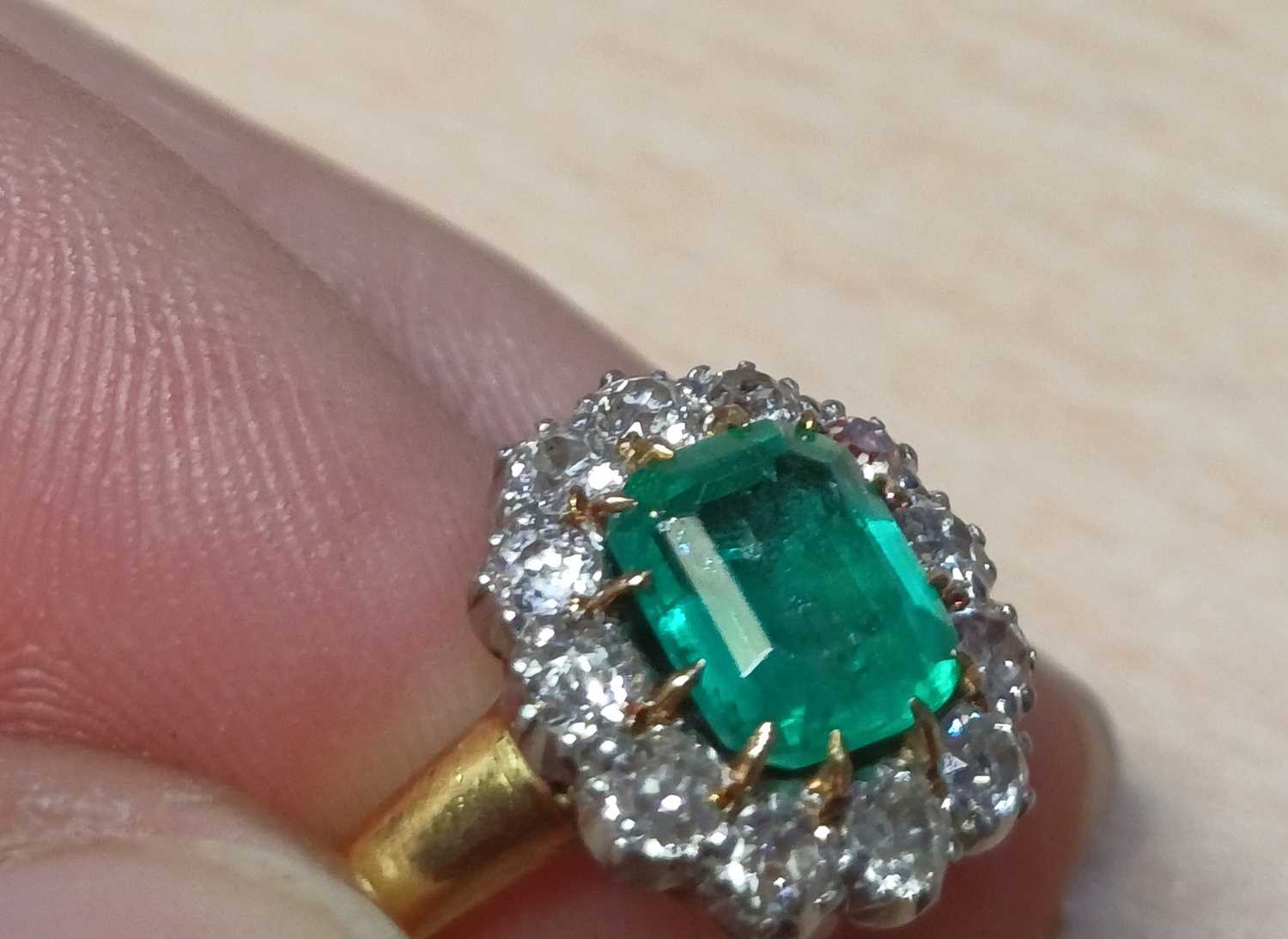 An Emerald and Diamond Cluster Ring the emerald-cut emerald in a yellow claw setting, within a - Image 7 of 9