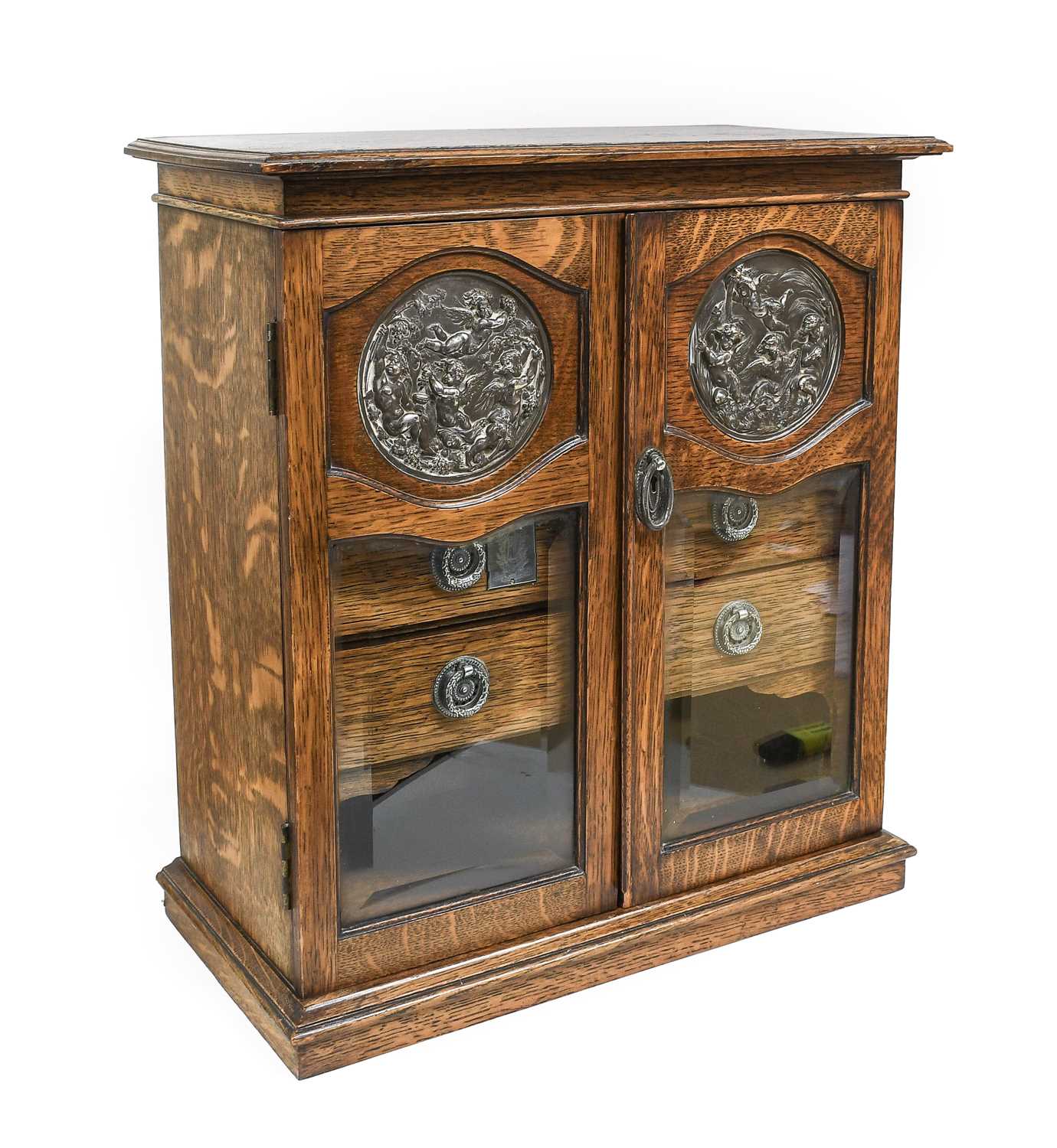 A Silver-Plate-Mounted Oak Smoker's Cabinet, the cavetto cornice over two glazed doors set with