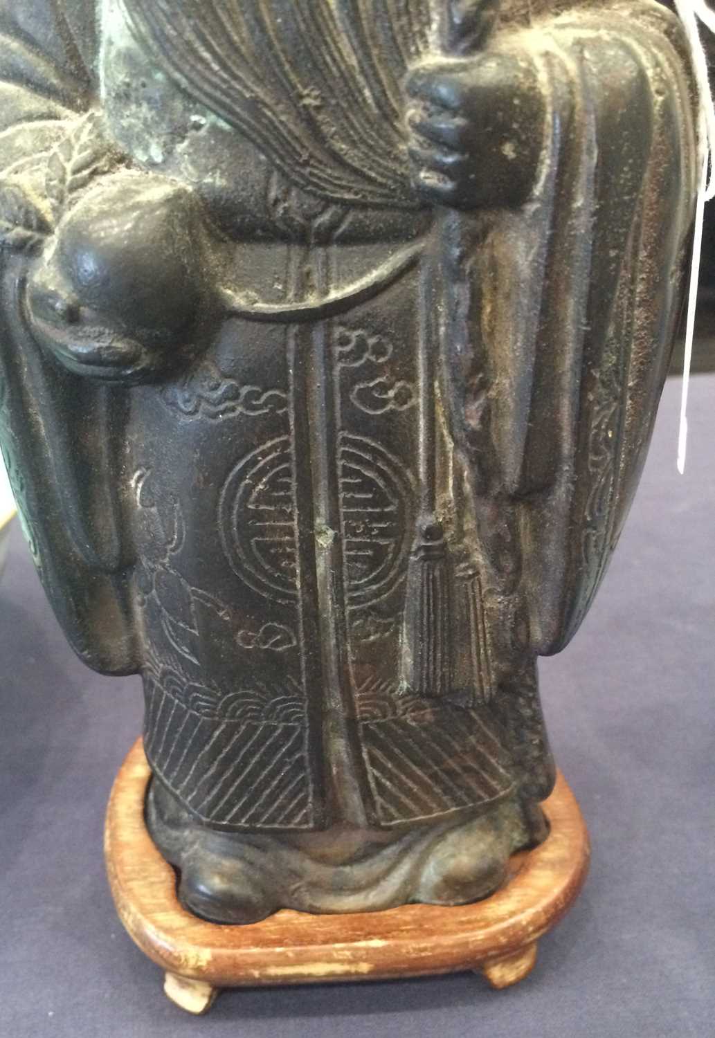A Chinese Bronze Figure of Shoulao, in Ming style, standing wearing flowing robes holding his - Image 3 of 26