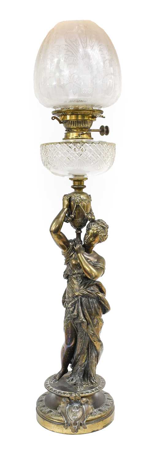 A Bronze Figural Oil Lamp. circa 1900, the cut glass reservoir supported by a maiden carrying a
