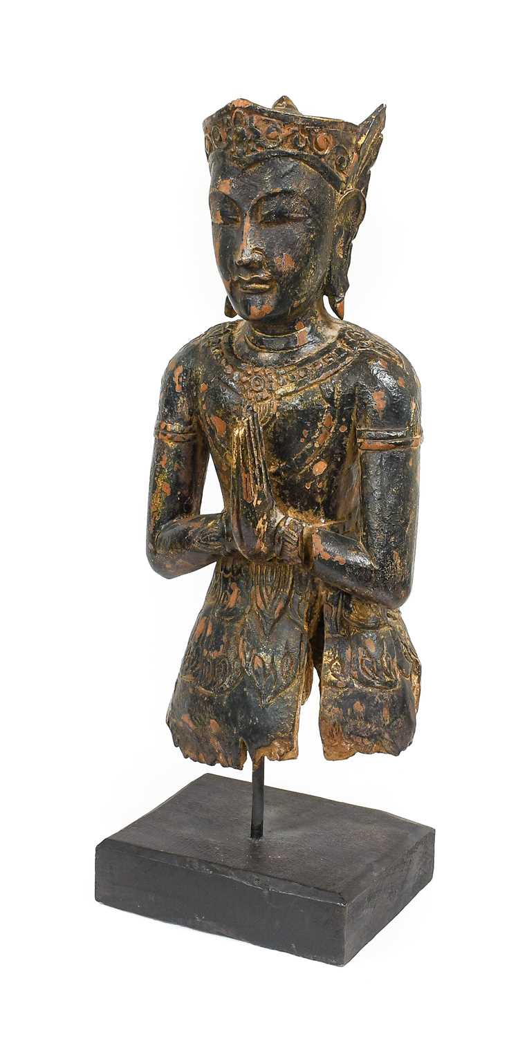 A South East Asian Lacquered Carved Wood Figure of a Divinty, in Kmer style, wearing scroll