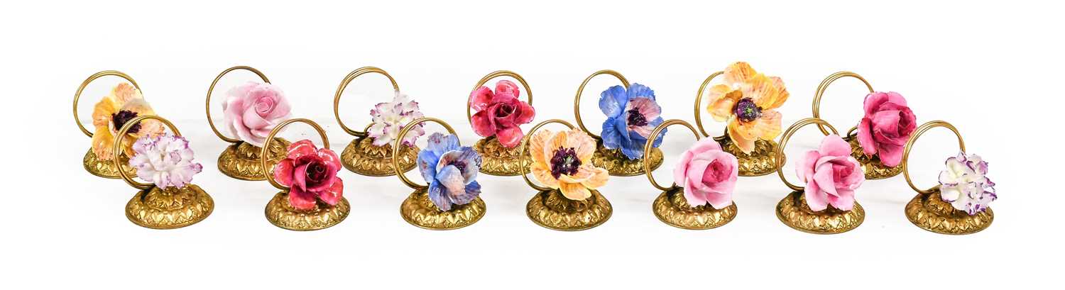 A Set of Fourteen Porcelain-Mounted Gilt Metal Place Card Holders, early 20th century, each with a