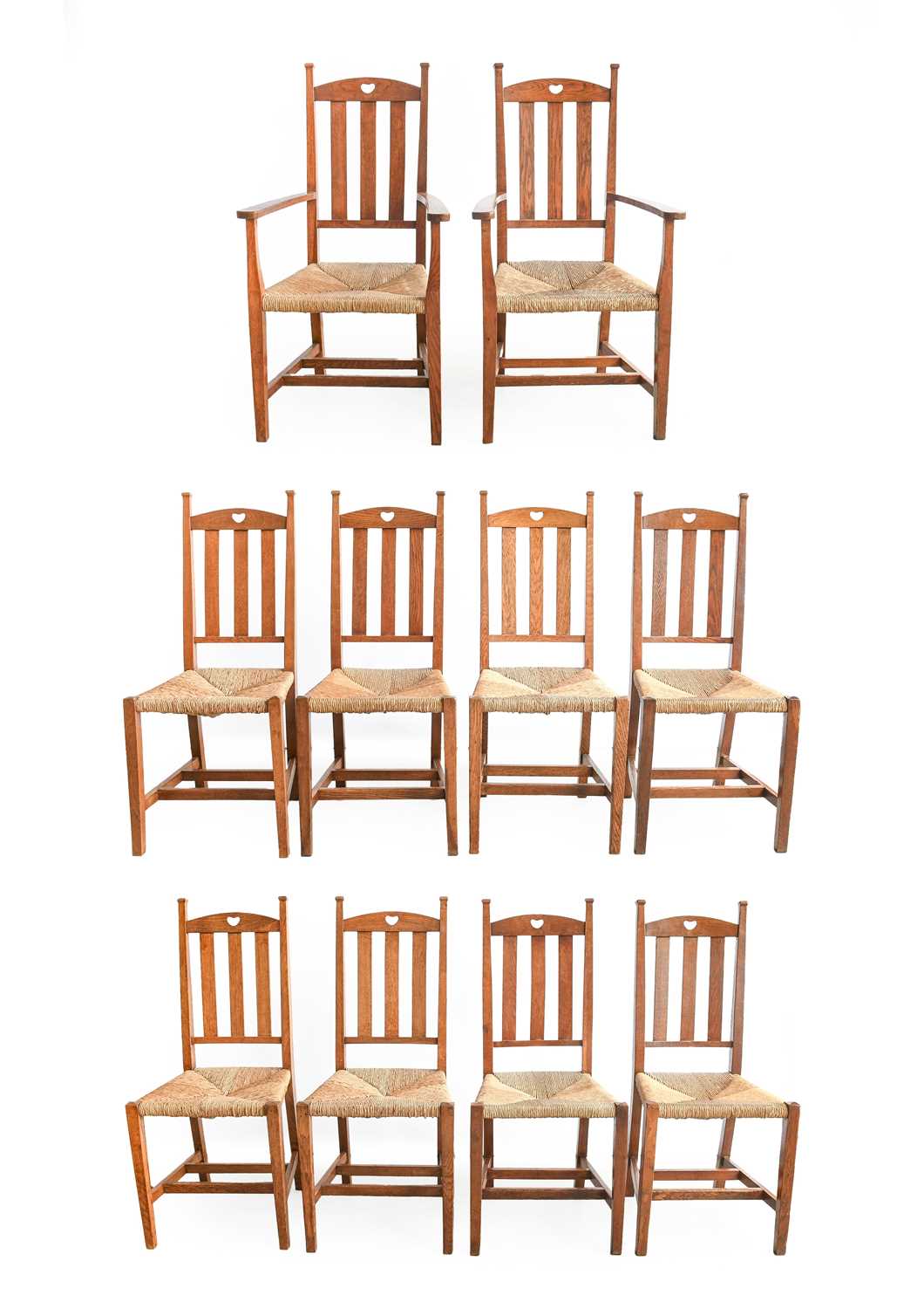 A Set of Ten (8+2) Arts & Crafts Oak Dining Chairs, made by William Birch, each with arched top rail