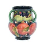 William Moorcroft (1872-1945): A Pomegranate Pattern Three-Handled Vase, on a green/blue ground,