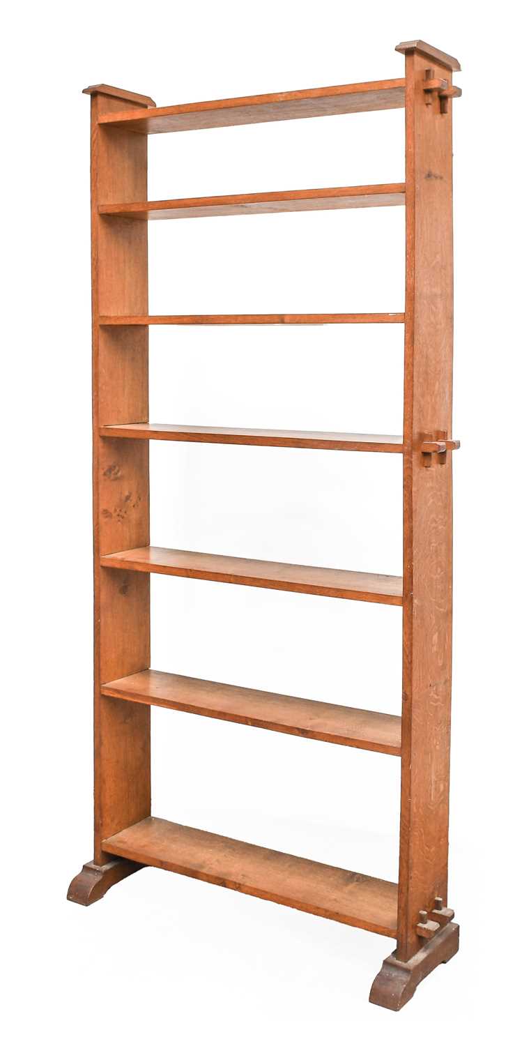 An Arts & Crafts Oak Open Pegged Bookcase, the shaped ends with pegged construction, seven fixed