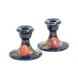 William Moorcroft (1872-1945): A Pair of Pomegranate Pattern Squat Candlesticks, on a blue ground,