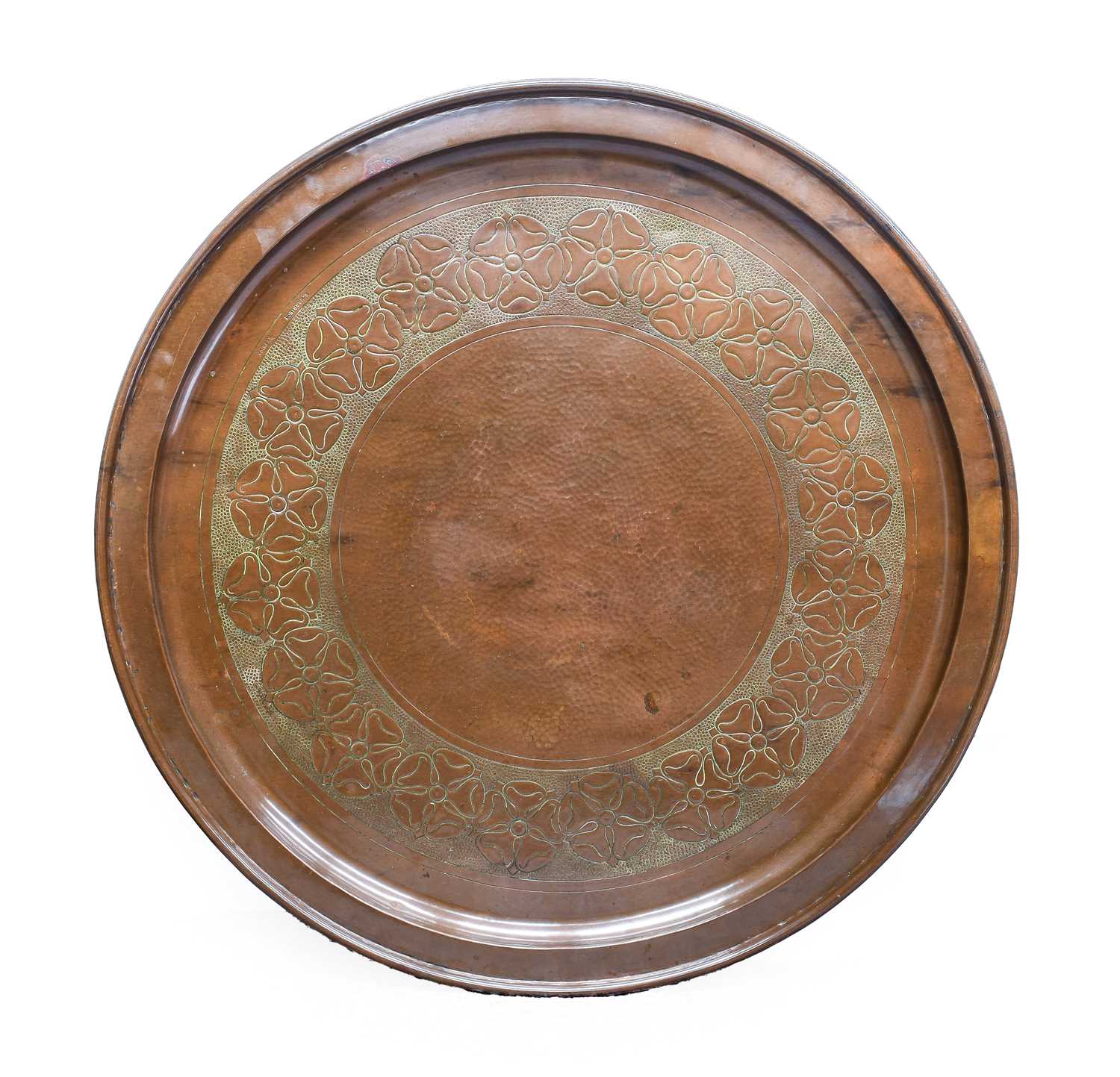 Ernest Harrison: An Arts & Crafts Circular Copper Charger, repoussé decorated with a border of