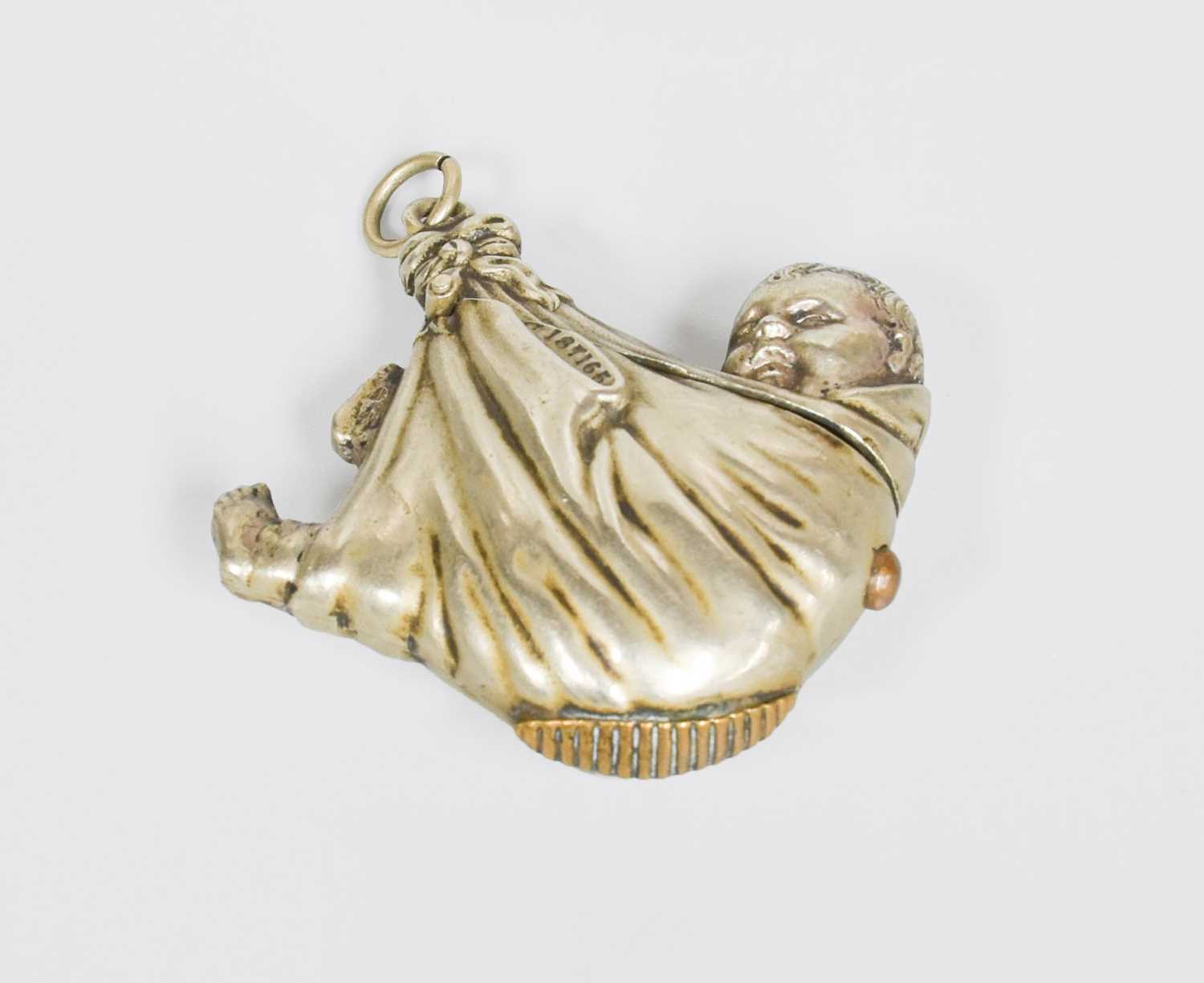 A Silvered Metal Vesta-Case, in the form of a baby in swaddling clothes, the base with striking