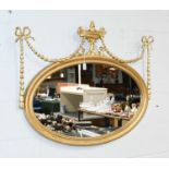 A Regency Style Oval Mirror, with urn and swag surmount, 100cm by 78cm