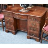 An Edwardian Cross-banded Mahogany Inlaid Desk, the bow front above a recess fitted with a