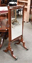 Mahogany Cheval Mirror, the turned frame with scrolling supports and brass capped castors, 64cm by