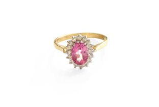 A 9 Carat Gold Pink Topaz and Diamond Cluster Ring, the oval cut pink topaz within a border of round