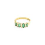 An 18 Carat Gold Emerald and Diamond Ring, five graduated oval cut emeralds in yellow claw settings,