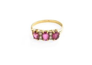 A Ruby and Diamond Ring, three oval cut rubies spaced by pairs of eight-cut diamonds, in yellow claw