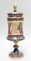 A 19th Century Vienna Type Porcelain Urn and Cover, on stemmed foot, with enamelled frieze depicting