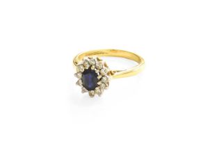 An 18 Carat Gold Sapphire and Diamond Cluster Ring, the oval cut sapphire within a border of round