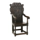 A Joined Oak Wainscot-Type Armchair, the carved top rail above a moulded back support carved with