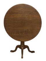 A George III Oak Circular Tripod Table, late 18th century, the flip-top on a vasiform support with