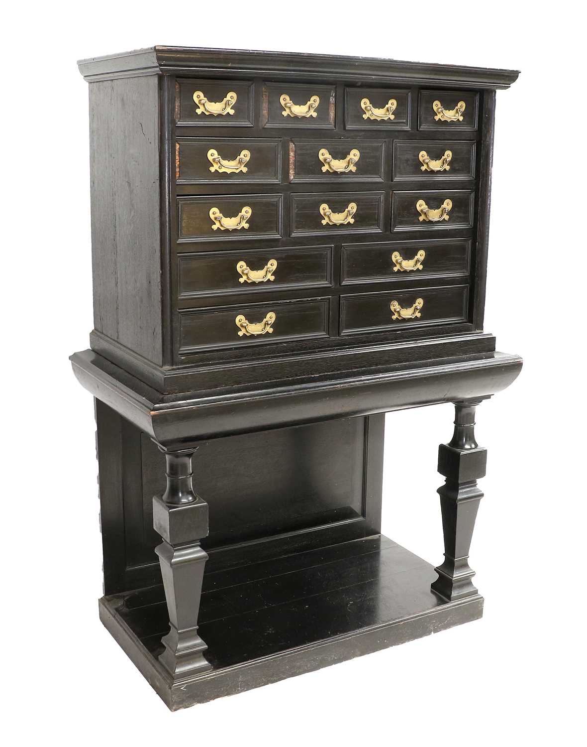 An Ebonised and Oak-Lined Cabinet on Stand, the moulded top above an arrangement of fourteen small