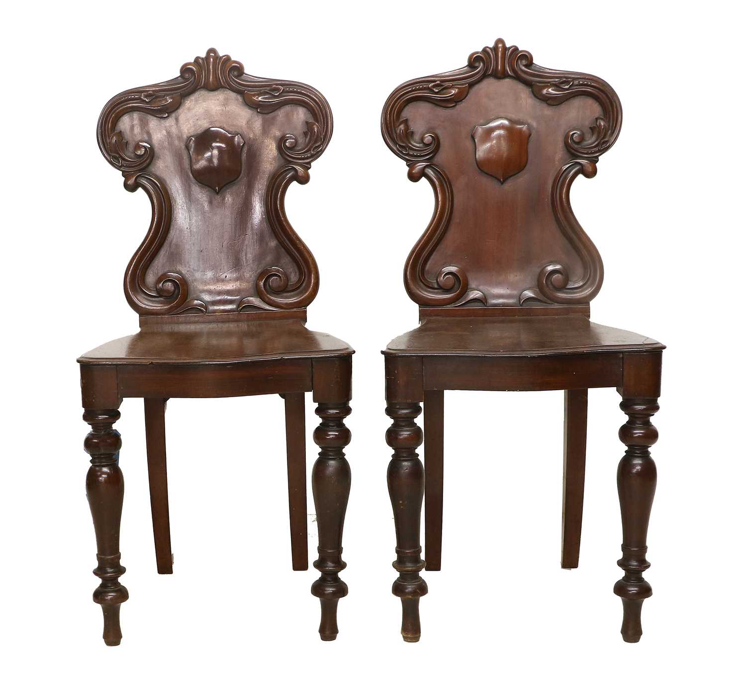 A Pair of Victorian Mahogany Hall Chairs, mid 19th century, the scrolled and carved back supports