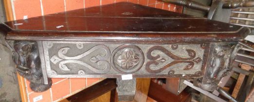 Victorian gothic carved oak corner shelf having bold carving of grotesque masks flanking a single