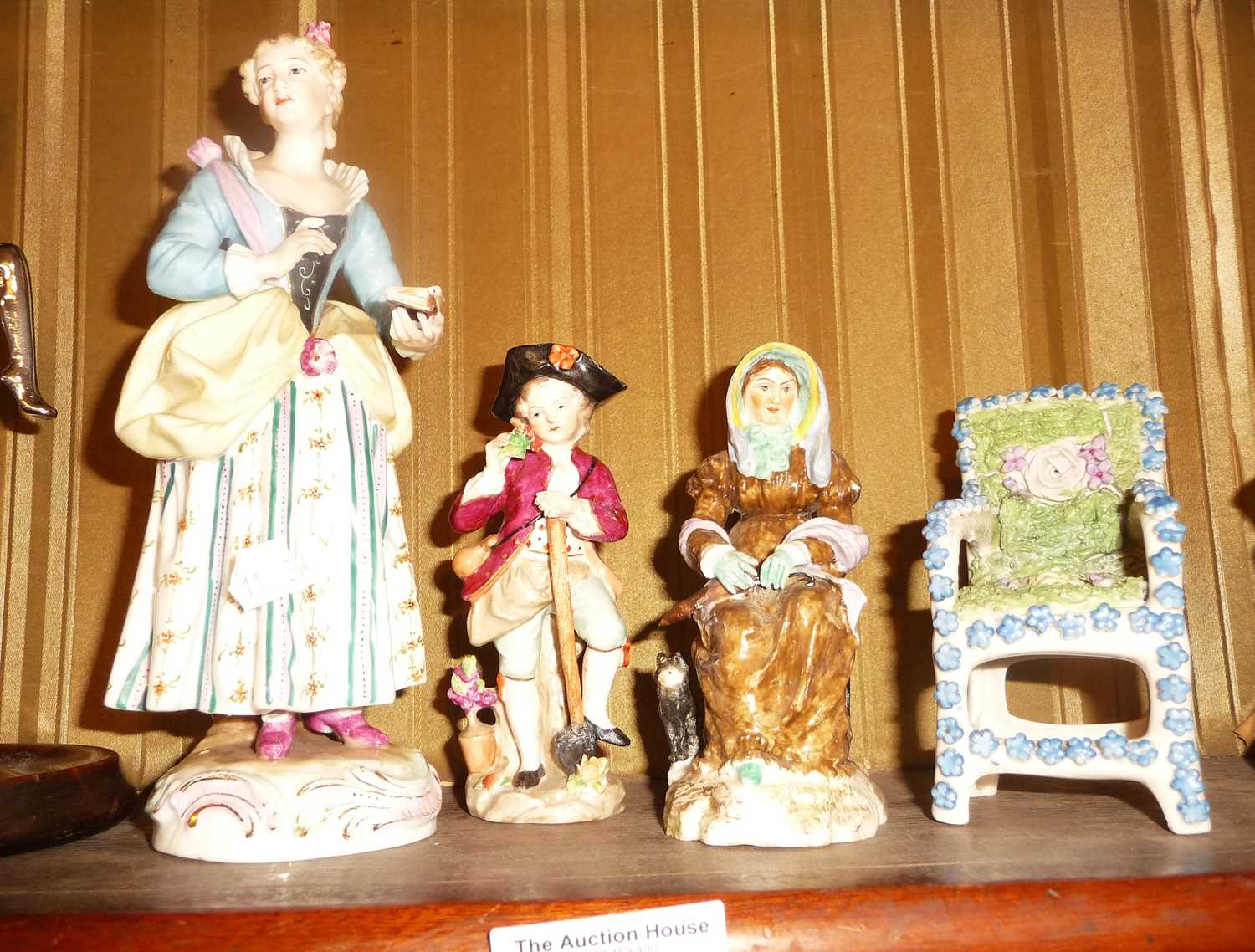 Three porcelain figurines and a porcelain moss and flower covered chair