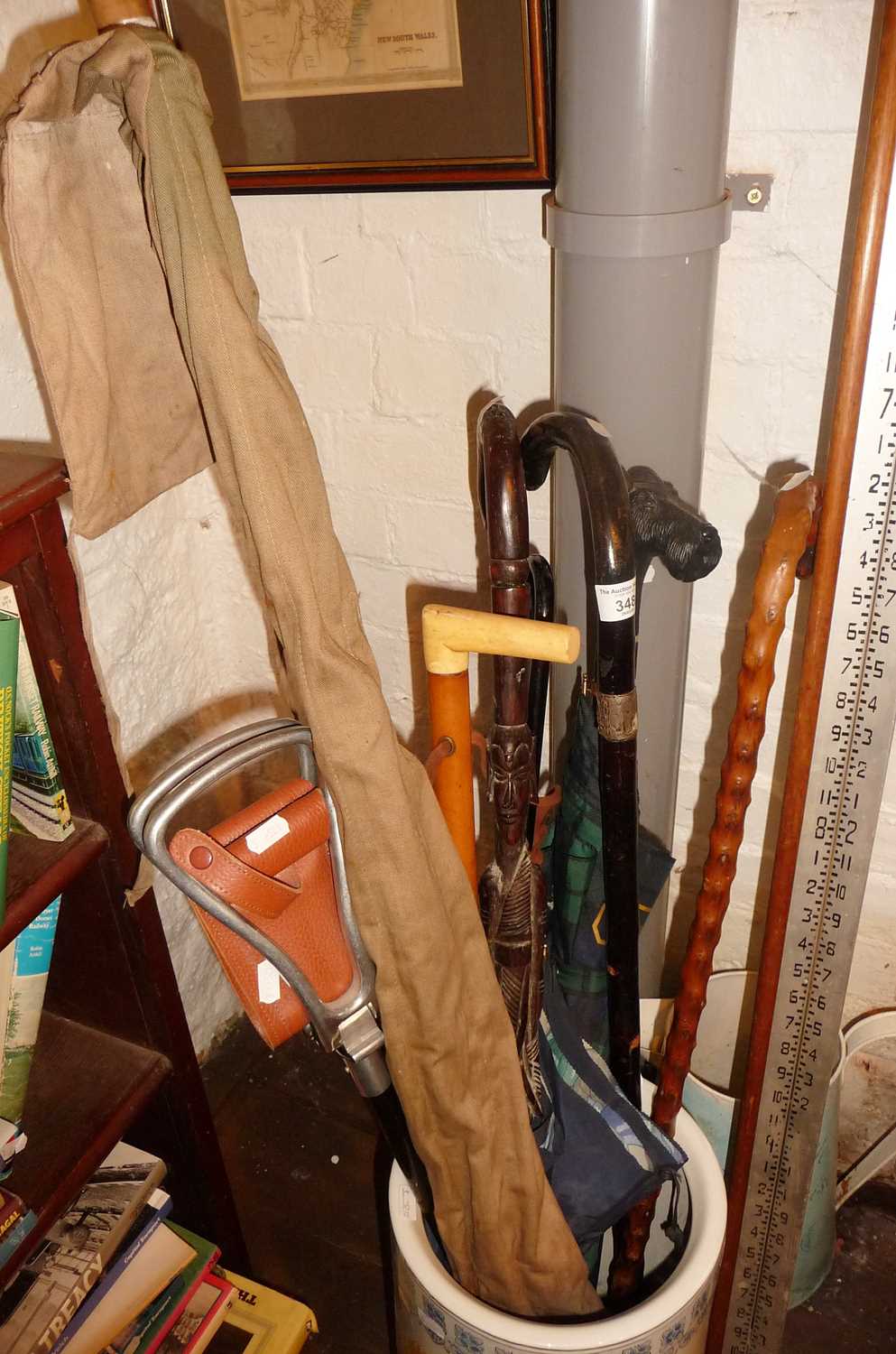 Collection of assorted walking sticks, a shooting stick, a fishing rod, an African spear and a