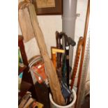 Collection of assorted walking sticks, a shooting stick, a fishing rod, an African spear and a