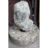 A Celtic stone head of a man, 14" tall, standing with an old grindstone