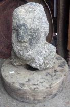 A Celtic stone head of a man, 14" tall, standing with an old grindstone