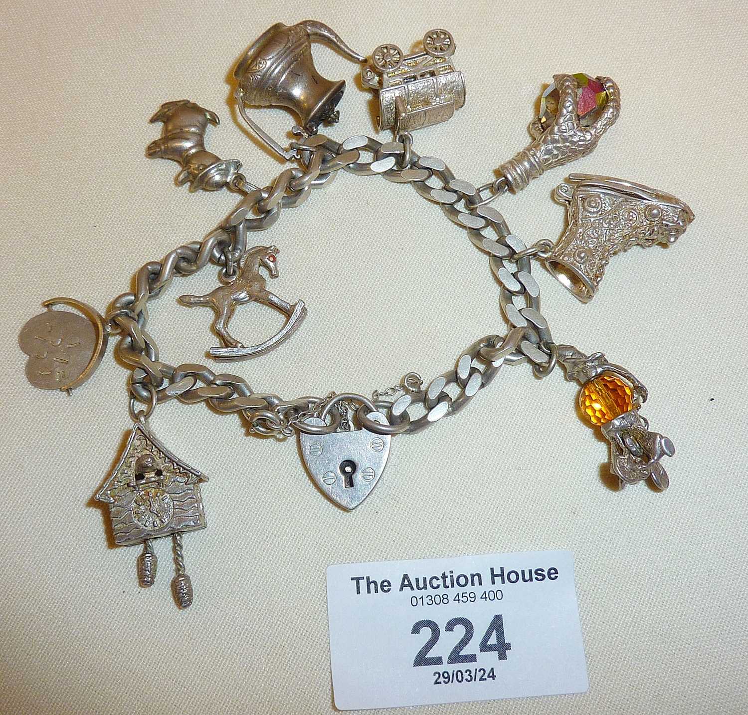 Vintage heavy silver charm bracelet with nine charms - some opening. Has a padlock clasp, and weighs