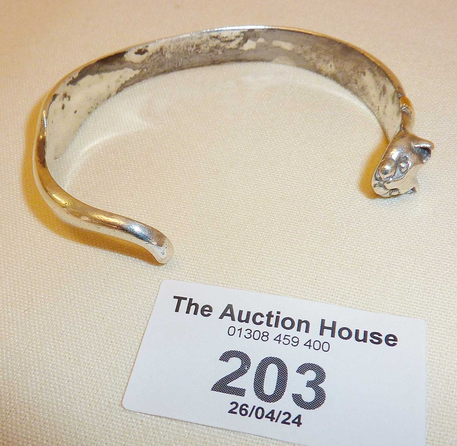 White metal bangle in the form of a cat, with rubbed marks