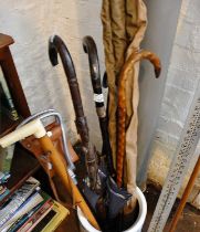 Collection of assorted walking sticks, a shooting stick, a fishing rod, an African spear and a