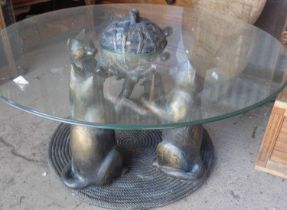 Circular glass coffee table supported by four resin cats