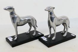 A pair of white metal, Art Deco style dog figures on black bases, approximately 20 cm (h). [2].