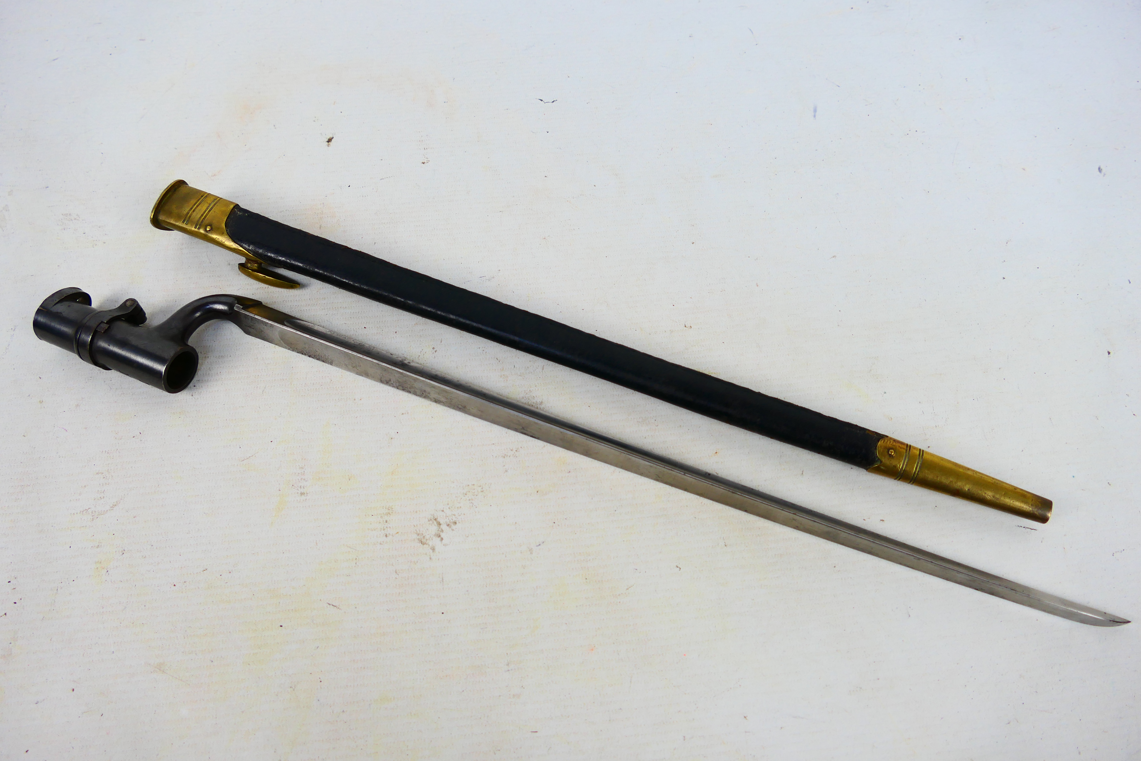 A pattern 1853 socket bayonet, 43 cm (l) triangular blade, with brass mounted scabbard.